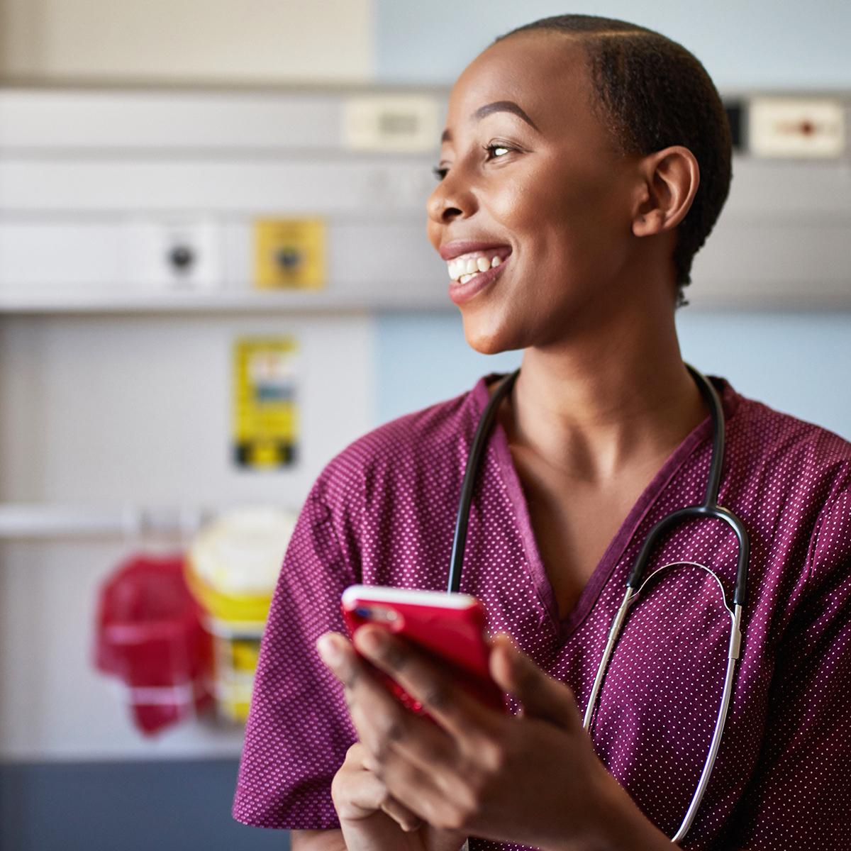 Nurse using a smartphone with patient in background