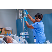 nurse hangs new iv bag with monitor in the background